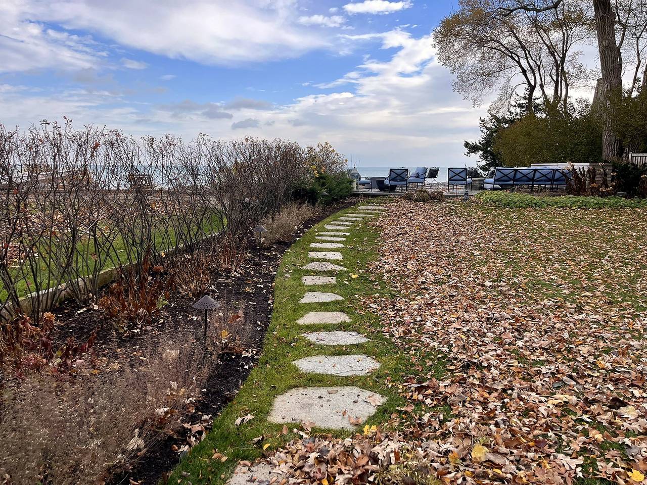 Stepping stones through fall leaves along a native border toward the lake