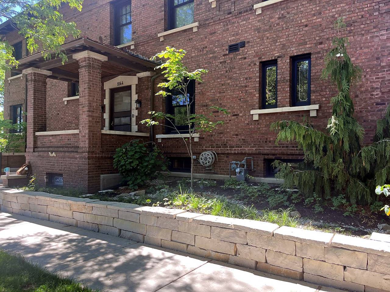 Dry laid limestone wall and new native planting in front of a brick house